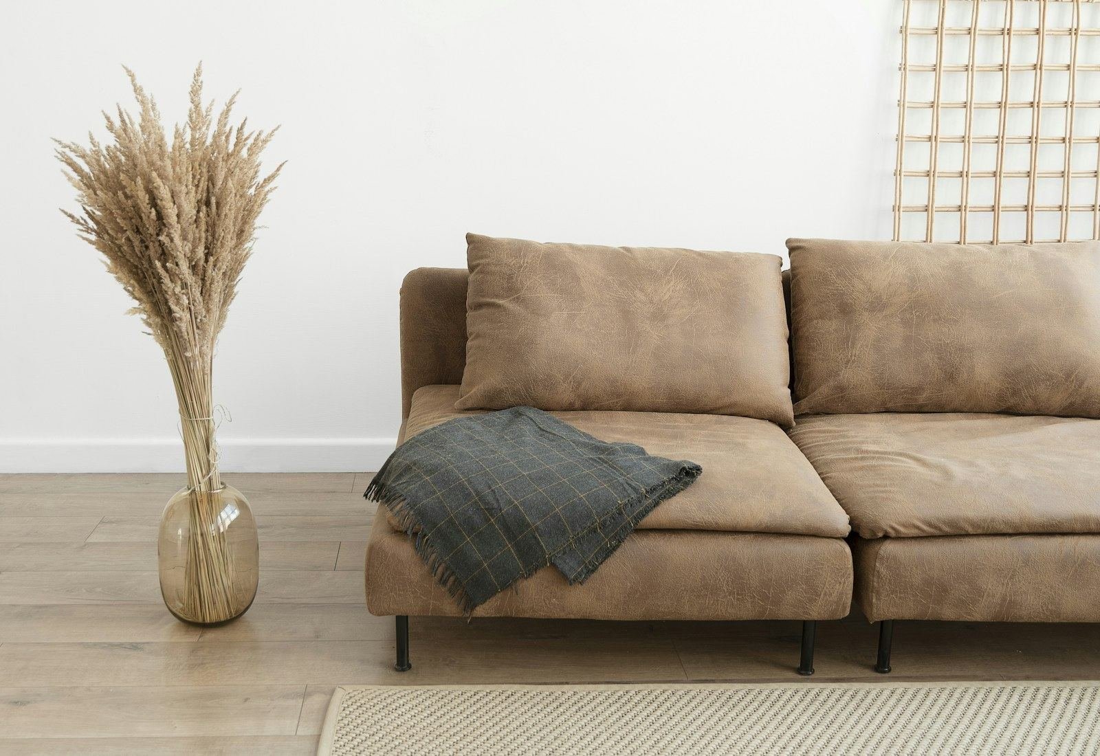 An upholstered sofa with dried grasses in a sunlit studio