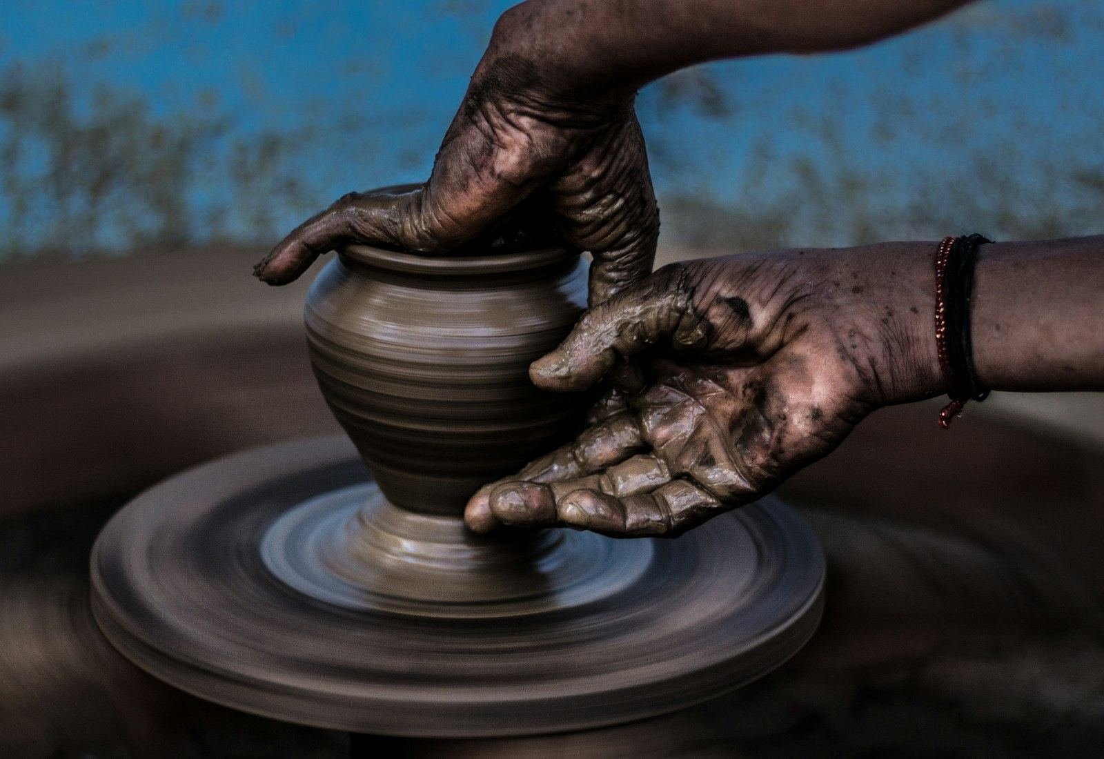 Hands throwing a stoneware bowl on a potter's wheel